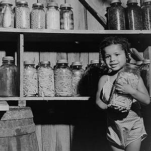 A young girl holding canned vegetables